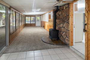 Family room with a wood stove, ceiling fan, and a drop ceiling