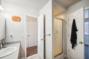 Bathroom with vanity, a shower with door, and a textured ceiling