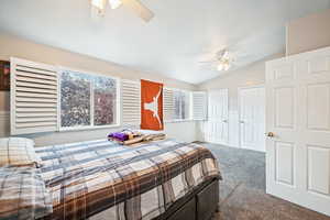 Bedroom with ceiling fan, lofted ceiling, and carpet