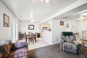 Living room with a textured ceiling, light carpet, and ceiling fan