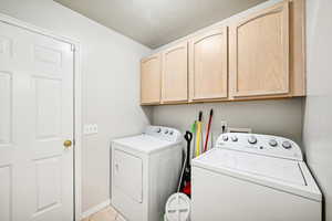 Clothes washing area featuring independent washer and dryer, cabinets, a textured ceiling, and light tile patterned floors