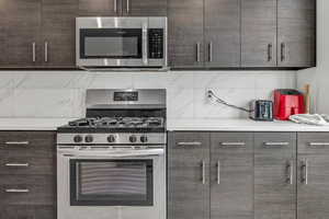 Kitchen featuring backsplash, dark brown cabinets, and stainless steel appliances