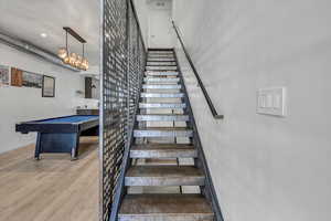 Stairway with hardwood / wood-style floors, a chandelier, and pool table