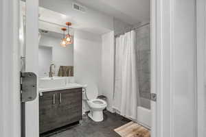 Full bathroom with tile patterned flooring, vanity, shower / bath combo with shower curtain, and toilet