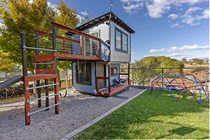 Back of property with a custom built play house/swing set and gorgeous landscaping.