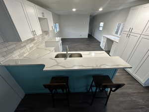 Kitchen featuring white cabinetry, kitchen peninsula, dark hardwood / wood-style flooring, and sink