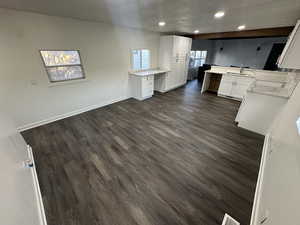 Kitchen featuring white cabinetry, a textured ceiling, sink, dark wood-type flooring, and kitchen peninsula