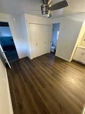 Unfurnished bedroom featuring a closet, dark hardwood / wood-style flooring, ceiling fan, and connected bathroom