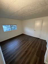 Spare room with dark hardwood / wood-style flooring and a textured ceiling