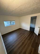 Spare room with dark wood-type flooring and a textured ceiling