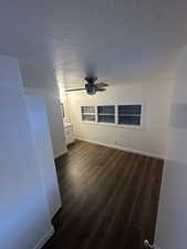 Unfurnished room featuring a textured ceiling, dark hardwood / wood-style floors, and ceiling fan