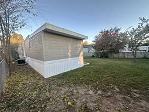 View of side of property featuring cooling unit and a yard