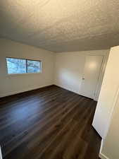 Spare room featuring dark hardwood / wood-style flooring and a textured ceiling