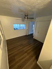 Unfurnished bedroom featuring a textured ceiling, dark hardwood / wood-style floors, ceiling fan, and a closet