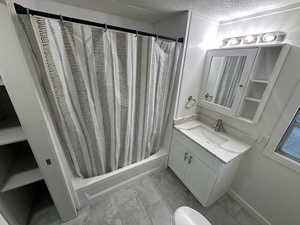 Bathroom with vanity, a textured ceiling, and shower / bathtub combination with curtain