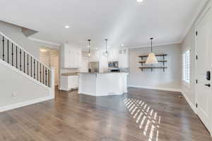 Kitchen with pendant lighting, stainless steel appliances, white cabinetry, and a center island with sink