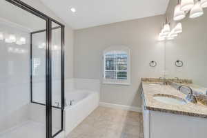 Bathroom with tile patterned floors, vanity, shower with separate bathtub, vaulted ceiling, and a chandelier