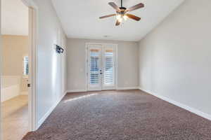 Primary bedroom with french doors and ceiling fan