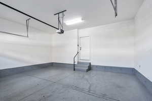 Garage featuring a garage door opener, painted floors