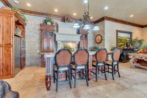 Clubhouse kitchen with a chandelier, decorative light fixtures, a kitchen bar, and crown molding