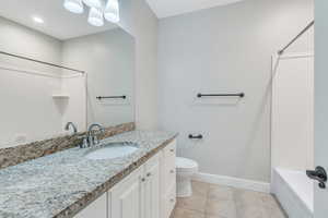 Full bathroom with toilet, vanity, tile patterned flooring, and shower / washtub combination