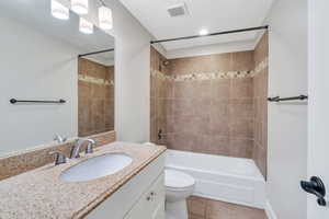 Full bathroom featuring vanity, tile patterned floors, toilet, and tiled shower / bath