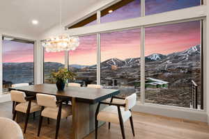 Dining area featuring hardwood / wood-style flooring, a mountain view, vaulted ceiling, and a notable chandelier