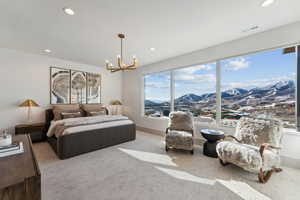 Carpeted bedroom with a mountain view, a notable chandelier, and multiple windows