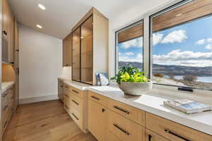 Kitchen with light brown cabinets, a water view, light hardwood / wood-style flooring, and vaulted ceiling