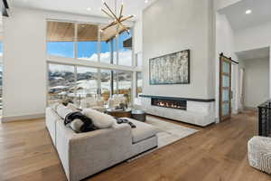 Living room featuring a barn door, a high ceiling, and light hardwood / wood-style flooring