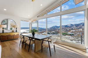 Dining space with light wood-type flooring, a water and mountain view, a healthy amount of sunlight, and high vaulted ceiling