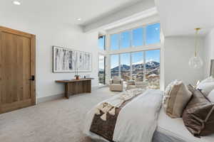 Bedroom with high vaulted ceiling, light carpet, and a mountain view