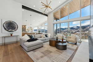 Living room with an inviting chandelier, a mountain view, light wood-type flooring, and high vaulted ceiling