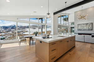 Kitchen with a mountain view, a center island with sink, light brown cabinets, sink, and light hardwood / wood-style flooring