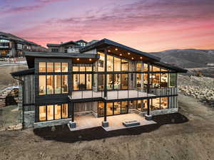 Back house at dusk featuring a mountain view and a patio area