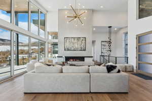 Living room with a towering ceiling, a mountain view, light wood-type flooring, and a notable chandelier