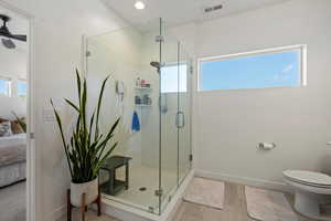 Bathroom featuring walk in shower, ceiling fan, a healthy amount of sunlight, and toilet