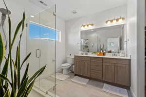 Bathroom with vanity, tile patterned floors, toilet, and a shower with door