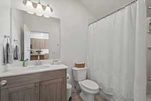 Bathroom with tile patterned flooring, a shower with shower curtain, vanity, lofted ceiling, and toilet