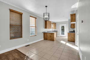 Kitchen featuring pendant lighting, plenty of natural light, kitchen peninsula, and ornamental molding