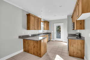 Kitchen featuring light tile patterned flooring, sink, kitchen peninsula, and stainless steel appliances