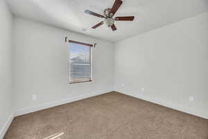 Carpeted spare room featuring ceiling fan