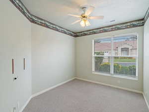 Carpeted spare room featuring a textured ceiling and ceiling fan