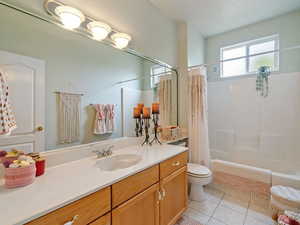 Full bathroom featuring tile patterned flooring, vanity, toilet, and shower / bathtub combination with curtain