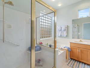 Bathroom featuring tile patterned flooring, shower with separate bathtub, and vanity