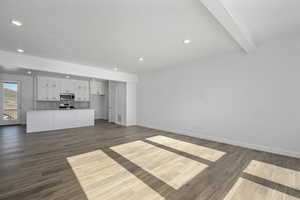 Unfurnished living room with beamed ceiling and dark hardwood / wood-style flooring