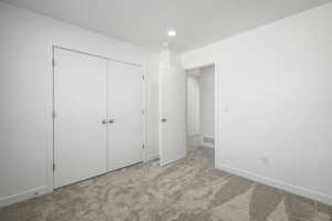 Unfurnished bedroom with light colored carpet and a closet