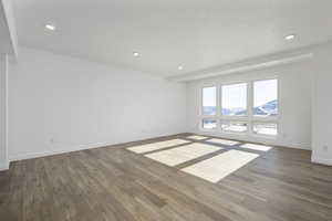 Empty room featuring a textured ceiling and dark hardwood / wood-style floors