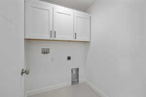 Laundry area featuring hookup for an electric dryer, light tile patterned flooring, cabinets, and hookup for a washing machine