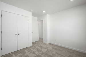 Unfurnished bedroom with light carpet and a closet